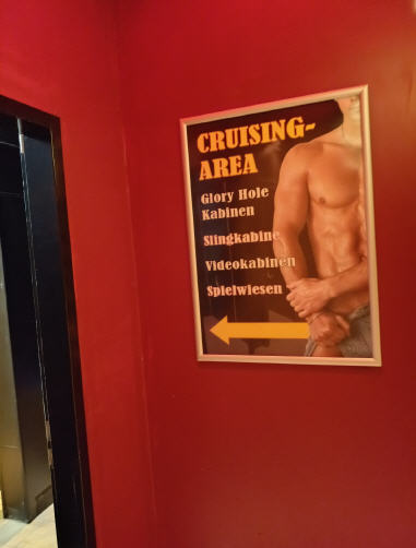 Rotes Schild im Haus: Cruising-Area, Glory Hole, Kabinen, Slingkabine, Videokabinen, Spielwiesen.