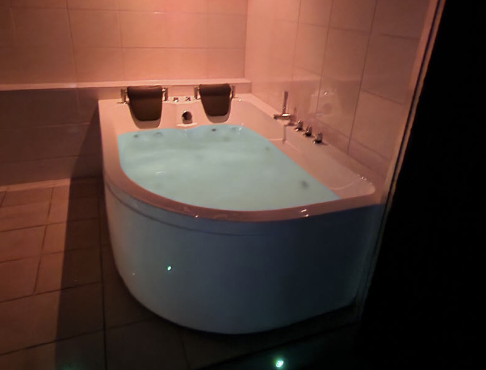 Eckwhirlpool mit zwei Nackenkissen und türkisem Wasser.